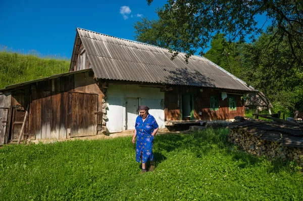 Senior woman near old wooden house — Stock Photo, Image