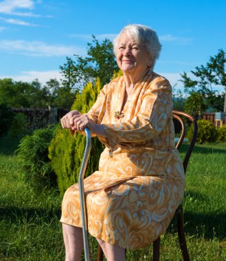 Old woman sitting on a chair with a cane clipart