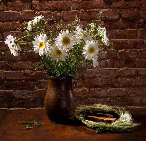 Daisies in vase and bakery pieces of  bread — Stock Photo, Image