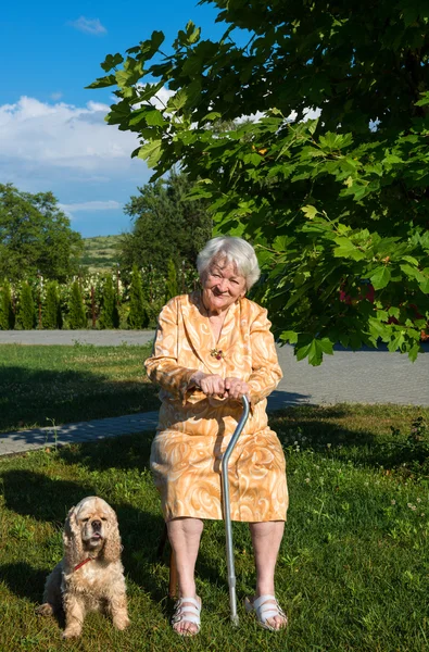 Alte Frau sitzt auf einem Stuhl mit einem Stock — Stockfoto