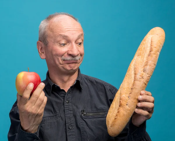 Сомневающийся человек с яблоком и багетом — стоковое фото