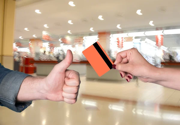 Woman holding credit card, man gesturing thumb up