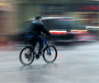 bisikletçi hareketli yağmurlu günde caddeden aşağı sürme