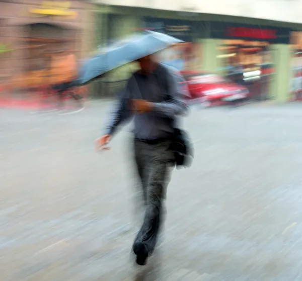 Homem caminhando pela rua em um dia chuvoso — Fotografia de Stock