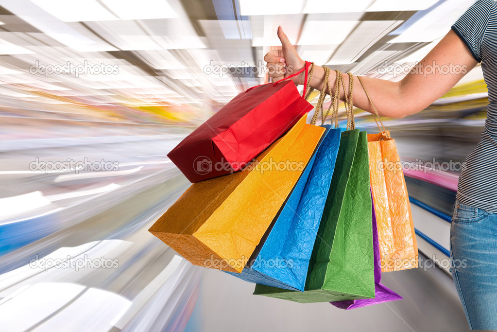Woman holding shopping bags and gesturing thumb up