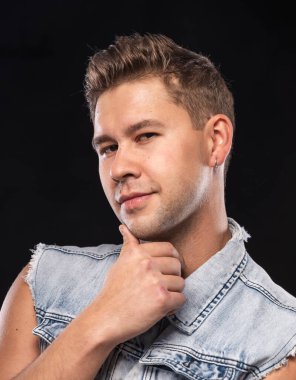 Stüdyoda siyah arka planda poz veren gülümseyen yakışıklı adamın portresi.