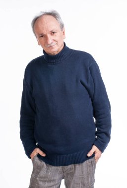 Stüdyoda beyaz arka planda poz veren süveter giyen kıdemli adam.