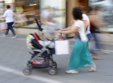 Bebek arabasında yürümekte olan çocuğu olan bir anne. Odaklanmamış resim