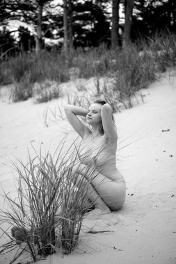 Açık havada poz veren güzel çıplak genç bir kadın. Çıplakken seksi Yazın sahilde eğleniyor