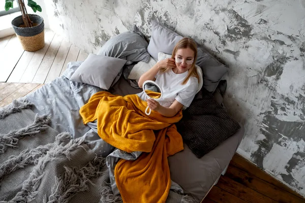 Jonge vrouw bewondert zichzelf in spiegel terwijl in bed Rechtenvrije Stockfoto's