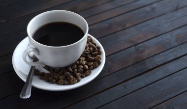 Bir fincan espresso kahve, kahve çekirdekleri ve ahşap bir arka plan.