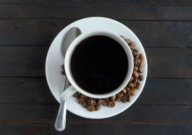 Üst manzara, bir fincan espresso kahve, kahve çekirdekleri ve ahşap arka plan.