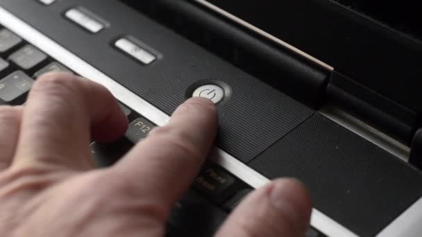 En man trycker på den bärbara datorn strömknappen med pekfingret — Stockvideo