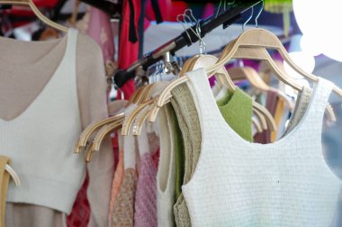 Bit pazarındaki dükkanda satılık ahşap askılarda asılı şık giysiler..