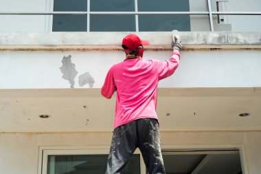 Eski renkleri beton duvarın yüzeyinden söken işçilerin arka görüntüsü