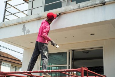 Eski renkleri beton duvarın yüzeyinden söken işçilerin arka görüntüsü