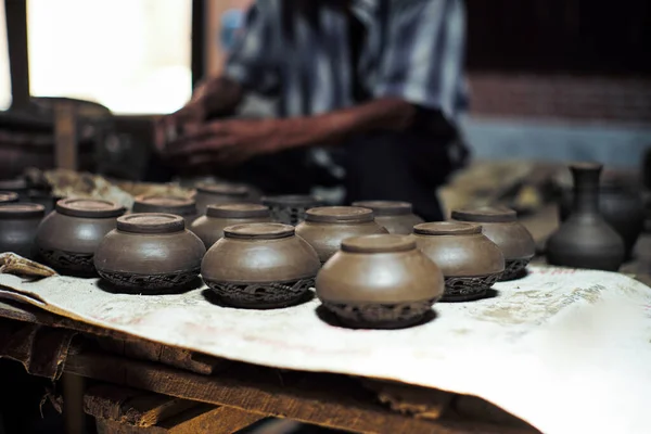 Group of clay jars in the production process with defocused old worker Group of clay jars in the production process with defocused old worker molding the clay work in background molding the clay work in background