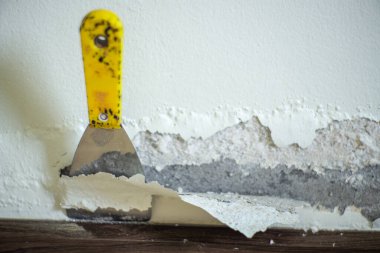 Beton duvarın su toplamış yüzeyine odaklanın. Bulanık malayla birlikte nemden şişmiş renkli duvar.