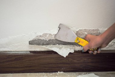 Beton duvarın su toplamış yüzeyine odaklanın. Duvardan tabloyu kaldıran işçinin bulanık eliyle nemden şişmiş renkli duvar.