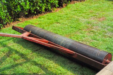 Arka planda bulanık yeşil manzarayla çimleri büyütürken çimlere bastırmak için yakın çekim ağır çelik davul.