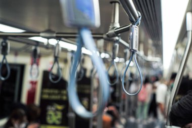 Arka planda bulanık bir grup yolcuyla metro treninin içindeki tırabzana odaklanın.
