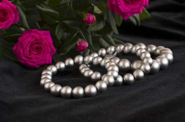 Pearl bracelets and bouquet of roses — Stock Photo, Image