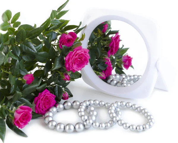 Pearl bracelets, bouquet of roses and a mirror — Stock Photo, Image