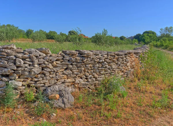 Traditional drywall in perspective as a fence of dirt road in Promina county in Croatia. Croatian drywall construction is a protected intangible cultural heritage of humanity by UNESCO.