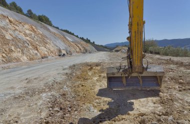 Construction site of an expressway through a rural area with a cut in the hill.