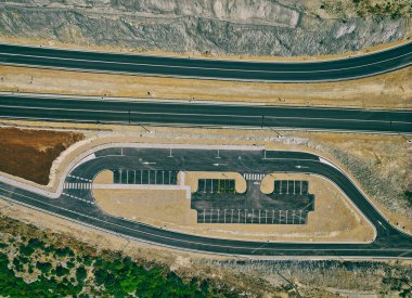 Construction site of an expressway through a rural area with a parking and rest area.