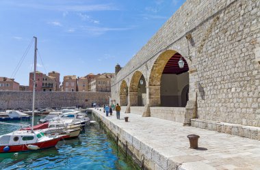 DUBROVNIK, CROATIA - APRIL 26 2022: The old town harbor atmosphere with local small boats moored