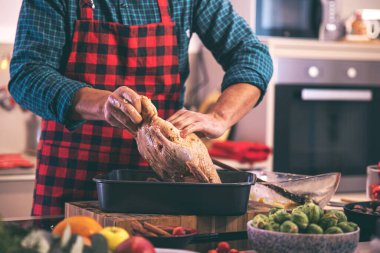 Erkek aşçının Noel için evde lezzetli ve sağlıklı bir kaz hazırlarken çekilmiş bir fotoğrafı. 