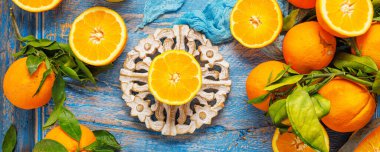 Olgunlaşmış taze portakalların ve ahşap arka planda yeşil yaprakların üst görüntüsü.