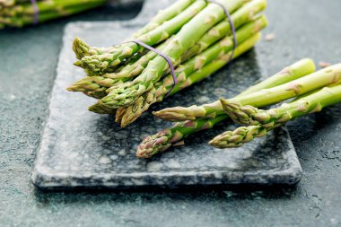 Köy arka planında bir sürü yeşil kuşkonmaz, çiftçi pazarında taze çiftlik sebzeleri.