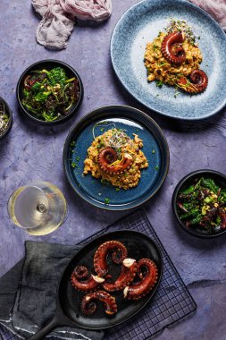 Mor zemin üzerinde ahtapot dokunaçları olan bir parça risotto. Üst görünüm