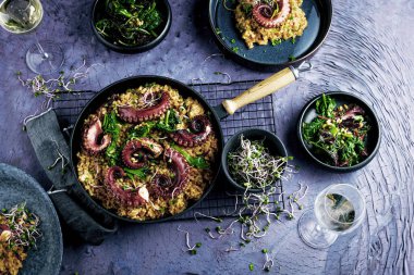 Mor zemin üzerinde ahtapot dokunaçları olan bir parça risotto. Üst görünüm