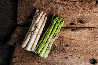 Ahşap arka planda çiğ taze yeşil ve beyaz kuşkonmaz. 