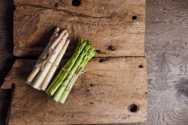Ahşap arka planda çiğ taze yeşil ve beyaz kuşkonmaz. 