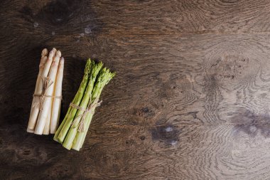 Ahşap arka planda çiğ taze yeşil ve beyaz kuşkonmaz. 