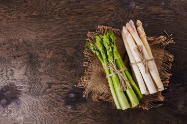 Ahşap arka planda çiğ taze yeşil ve beyaz kuşkonmaz. 