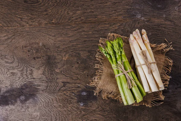 Ahşap arka planda çiğ taze yeşil ve beyaz kuşkonmaz. 