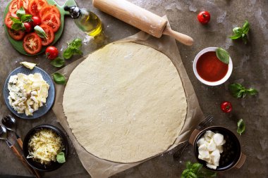 Pizza hamuru ve taze malzemelerle bezenmiş düz bir kompozisyon. Metin için boşluk