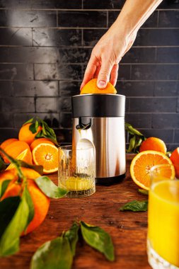 Mutfakta portakal suyu hazırlığı. Çerçevede - el sıkma suyu, meyve sıkacağı ve portakallar. Sağlıklı yaşam tarzı, vitaminler, parlak sulu meyveler..