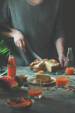 Ev yapımı şam fıstıklı havuçlu turtayı limon jölesiyle kesen kadın.