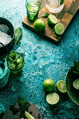 Taze mojito kokteyli, limonlu, naneli ve buzlu kavanozlu koyu mavi arka planda.
