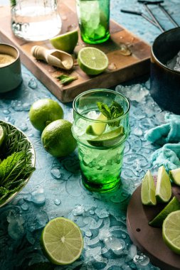 Taze mojito kokteyli, limonlu, naneli ve buzlu kavanozlu koyu mavi arka planda.