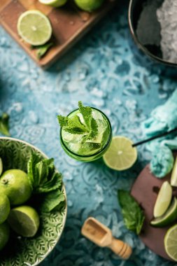 Taze mojito kokteyli, limonlu, naneli ve buzlu kavanozlu koyu mavi arka planda.