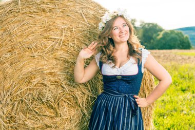 Geleneksel bir Bavyera Dirndl elbisesi içinde saman balyasına poz veren güzel bir kadın.. 