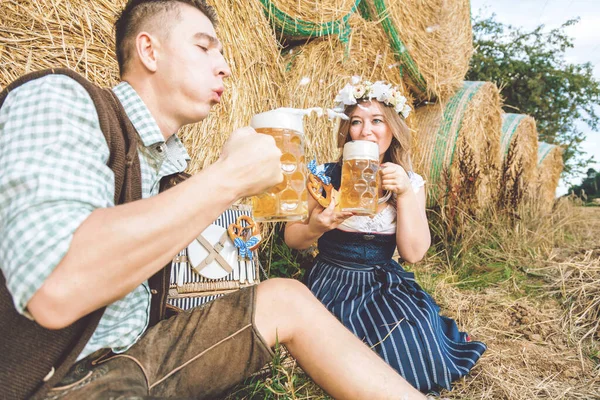 年轻的女人和男人 戴着啤酒杯 背对着干草包 Oktoberfest概念 — 图库照片