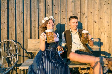 Bira bardakları ve tahta arka planda kraker olan genç bir kadın ve adam. Oktoberfest kavramı.